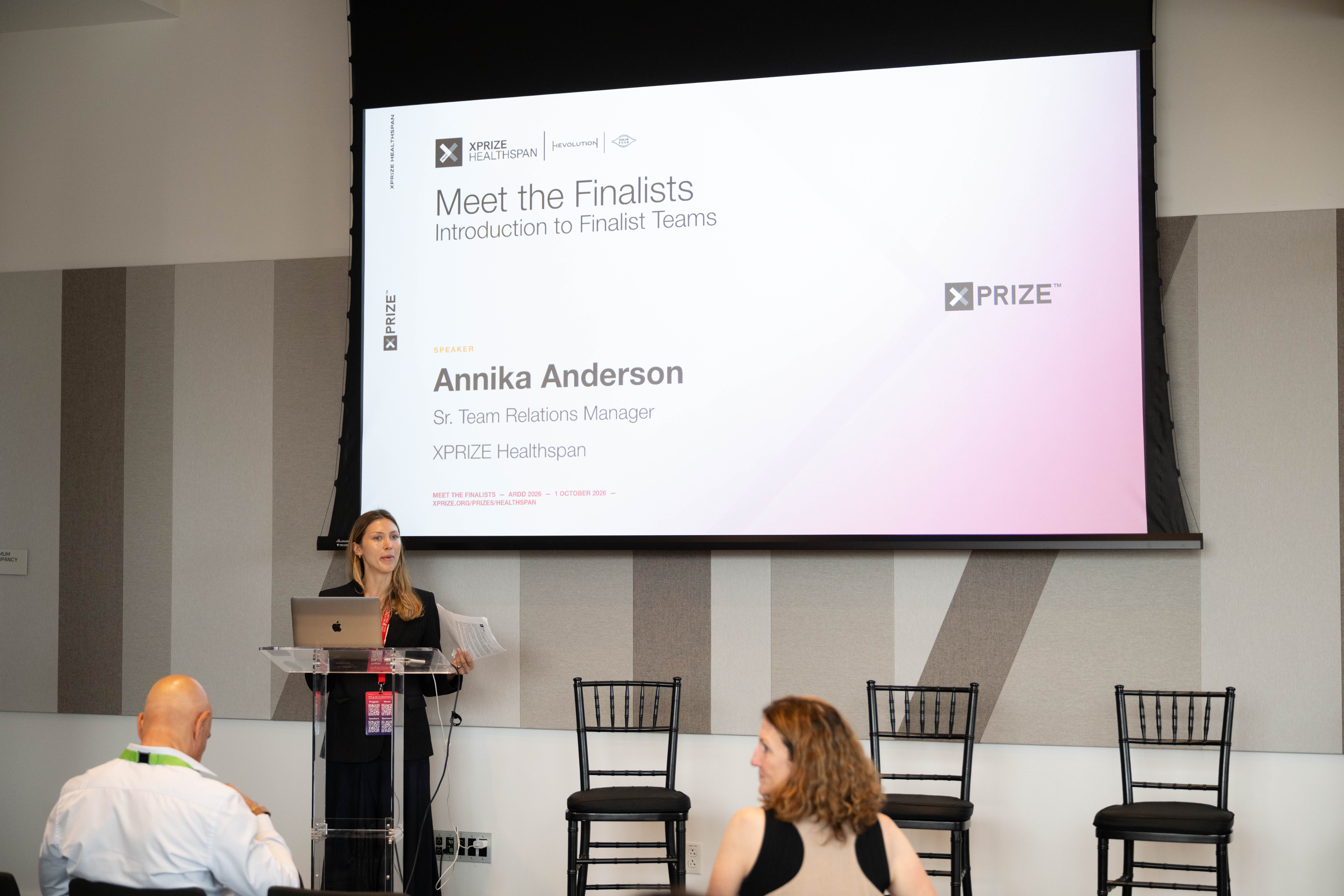 Annika Anderson at the Cedar Grove podium beneath her named XPRIZE Healthspan Meet the Finalists title slide.